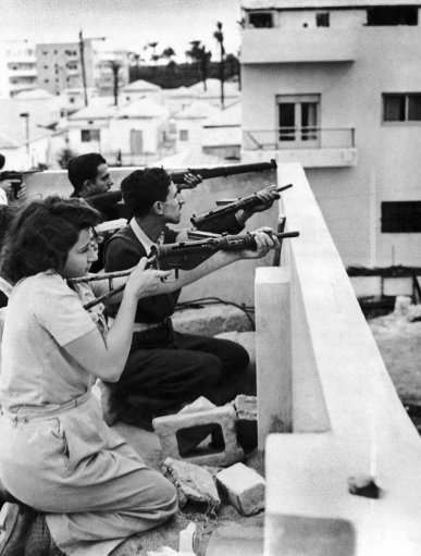 Members of the Jewish right-wing underground organization Irgun Zvai Leumi (National Military Organization in the Land of Israel) are armed with rifles, revolvers and automatic weapons as they take position on the rooftop of a Jewish house in case of Arab attack on the Jaffa - Tel Aviv border in the Manshiah Jewish quarter in Tel Aviv, Israel, on December 27, 1947. The Zionist guerrilla force began an armed revolt against British rule in Palestine. 