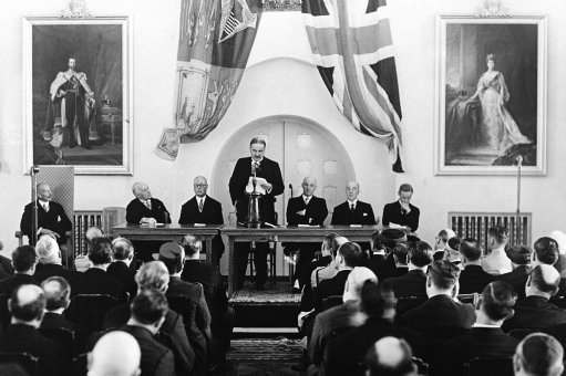 The royal commission to investigate conditions in Palestine started work at the reception held at the government house in Jerusalem, Israel on Nov. 12, 1936. Lord Peel, chairman of the royal commission, reading his opening speech. Sir Arthur Wauchope, high commissioner for Palestine is seen on left in armchair. The members of the commission are left to right: Sir Morris Carter, Sir Horace Rumbold, Vice-Chairman, Lord Peel, Sir Laurie Hammond, Sir Harold Morris, and Mr. Reginald.