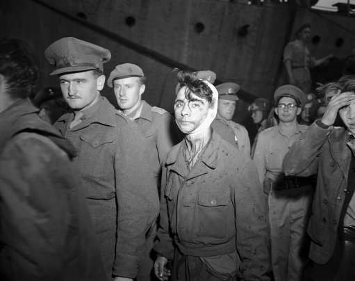 A young Jewish boy, wounded and bloody after the fight with British soldiers on board the refugee ship Knesset Israel, passes a line of soldiers to board the troopship Empire Heywood on Dec. 4, 1946 in Haifa, one of three vessels on which passengers from the refugee ship were deported.