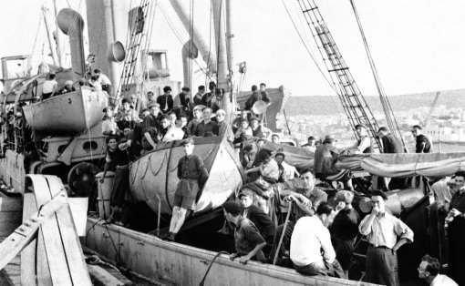 22 ton steamer arrested off Palestine with 400 refugees aboard after a month at sea. With 401 men, women and children huddled on the upper deck with cattle and poultry. The Greek-manned panama steamer Atratto was arrested inside territorial waters off Jaffa, Palestine, on July 17, 1939. By the minesweeper H.M.S. Sutton. She was escorted into Haiffa where the captain and crew are awaiting trial for attempting to smuggle refugees into Palestine. Though crowded in misery on the open deck $25 was the cost of the passage into Palestine, the fee not including bedding or food. Associated Press Photo Shows: The crowded decks of the S.S. Atratto, showing that even the lifeboat (center) was displaced with the great crowd on the steamers’ decks. These “Berths’ cost $25 a head. (AP Photo)