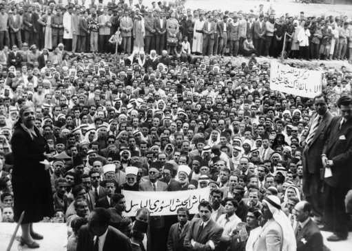 Some 10,000 of the 48,000 Palestine Arab Refugees who have settled in and around Damascus, Syria, staged a demonstration in Damascus, last week in April 1929 to express their gratitude to the Syrian Army for the recent Syria-Israel border clashes. They asked to be accepted as volunteers for the Syrian fighting forces so that they night fight back at Israel, upon which country they blame their present unhappy condition as refugees. Photo shows: An elderly lady addresses a great crowd of Palestine Arabs in the court-yard of the Army General Headquarters in Damascus. Her speech was among others heard there by Syrian Officers. 