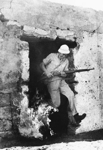 A volunteer trainee for the Hagana Leaps from a flaming house, rifle in hand on Dec. 30, 1947, during training near Tel Aviv as Jews prepare for fighting against Arabs as a result of the United Nations decision partitioning Palestine. The trainee has just set fire of the house, which formerly was an Arab home