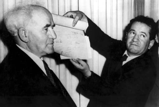 An official shows the signed document which proclaims the establishment of the new Jewish state of Israel declared by Prime Minister David Ben-Gurion, left, in Tel Aviv at midnight on May 14, 1948. The Jews declared independence in the new state of Israel as the 25-year British mandate over Palestine ends.