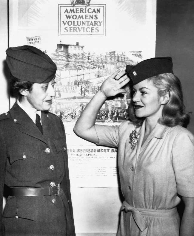 Mrs. Morton S. Stern (left) gets a salute from Claire Trevor after the movie actress had been inducted in the American womenÂs voluntary service in New York, Dec. 18, 1941. (AP Photo/John Rooney)