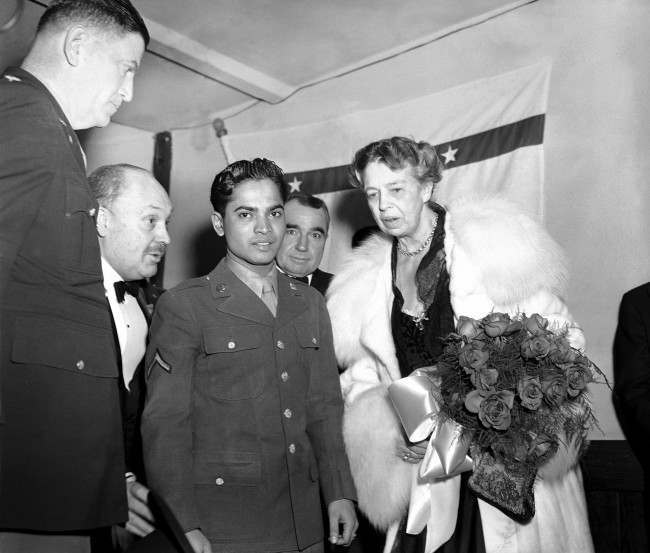 Eleanor Roosevelt holds a bouquet of roses as she stands with Sabu, the ÂElephant BoyÂ of movie fame, and now a soldier attached to Fort Meade, Md., at the president's birthday ball celebration at a USO post in the YMCS in Washington on Jan. 29, 1944. (AP Photo/GBF)