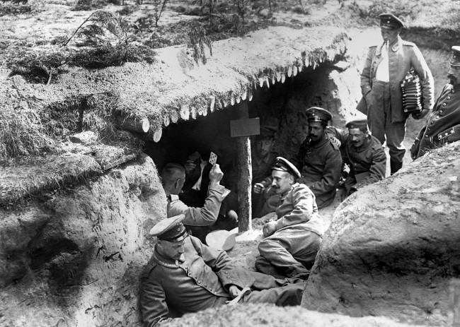 German soldiers of the 12th (2nd Brandenburg) Regiment playing cards in a dugout in a shallow trench in German-occupied Russian Poland during the First World War. One of the soldiers (far right) is holding an accordion.