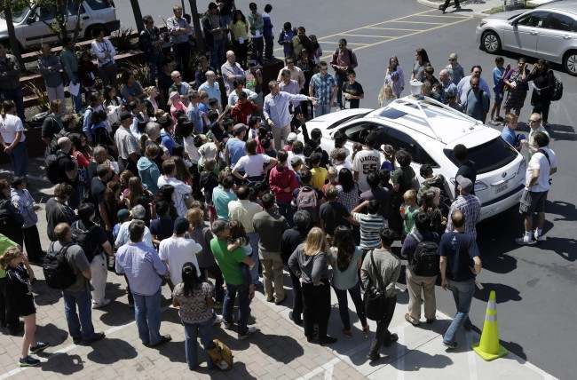 A crowd gathers around Google's self-driving car during a demonstration for employees and their children at Google headquarters in Mountain View, Calif., Thursday, April 25, 2013. (AP Photo/Marcio Jose Sanchez)