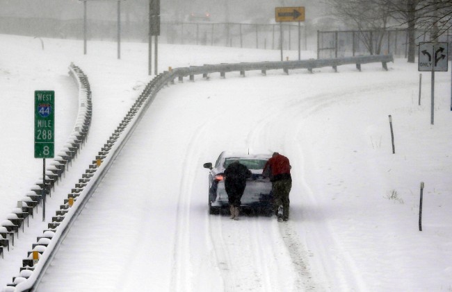 Two people help a stranded motorist up snow-covered exit ramp on I-44 Sunday, Jan. 5, 2014, in St. Louis. Snow that began in parts of Missouri Saturday night picked up intensity after dawn Sunday with several inches of snow on the ground by midmorning and more on the way. (AP Photo/Jeff Roberson)