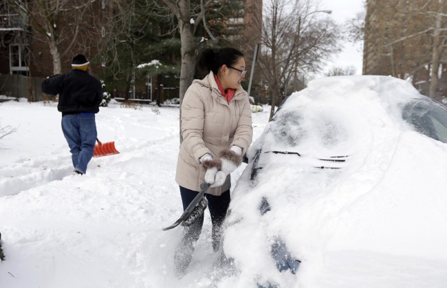 Cecy Wang, right, clears snow off her car as Samuel Scott, left, shovels a sidewalk Tuesday, Jan. 7, 2014, in St. Louis. As Missourians muddled through another frigid day Tuesday, the worst cold snap in nearly two decades was about to come to an end but many roads remained partly snow-covered two days after a winter storm dumped several inches of snow. (AP Photo/Jeff Roberson)
