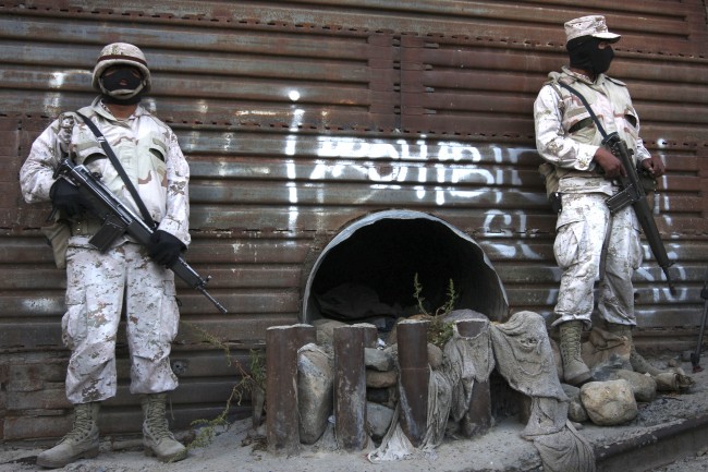 This June 4, 2010 file photo shows Mexican army soldiers standing guard next to a tunnel at the border wall in Tijuana, Mexico. More than 75 such underground passages have been found along the border since 2008, concentrated largely in California and Arizona. The job of searching these networks can be dangerous, so the U.S. Border Patrol is unveiling its latest technology in the underground war, a wireless, camera-equipped robot that can do the job in a fraction of the time. (AP Photo,File)