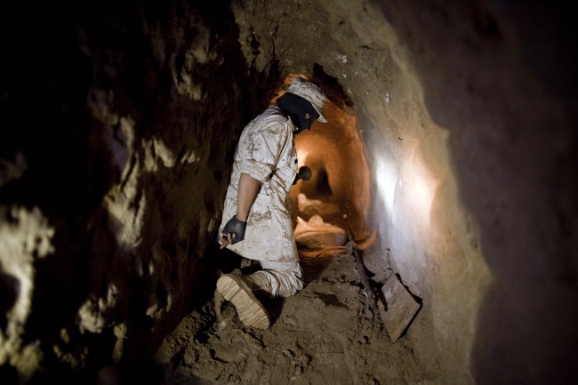 This Nov. 4, 2010 file photo shows a Mexican Army soldier using a flashlight to shows reporters a tunnel connecting warehouses on either side of California's border with Mexico in Tijuana. More than 75 such underground passages have been found along the border since 2008, concentrated largely in California and Arizona. The job of searching these networks can be dangerous, so the U.S. Border Patrol is unveiling its latest technology in the underground war, a wireless, camera-equipped robot that can do the job in a fraction of the time. (AP Photo/Guillermo Arias)