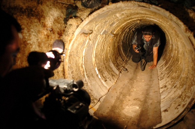 This July 8, 2004 file photo shows a Mexican federal agent crawls through a hidden tunnel, presumably used to transport drugs from Mexico to the U.S. The job of searching these networks can be dangerous, so the U.S. Border Patrol is unveiling its latest technology in the underground war, a wireless, camera-equipped robot that can do the job in a fraction of the time. (AP Photo/David Maung) 