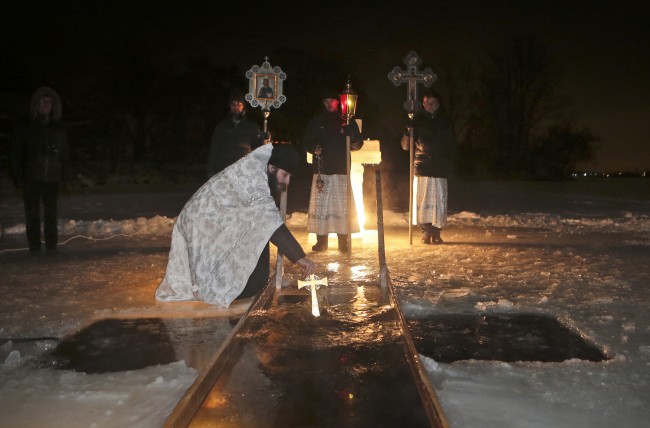 A Russian Orthodox priest blessing water in a river on Russian Orthodox Epiphany in the village of Sorokino, just outside Moscow, early Sunday, Jan. 19, 2014. The temperature in Moscow is -20C ( -4 F