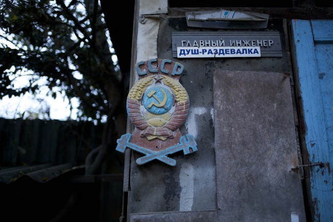 In this photo taken on Wednesday, Nov. 27, 2013, the colored state emblem of the USSR hangs on the door of the outhouse in the yard of the railroad house in the village of Vesyoloye outside Sochi, Russia. Signs read "Chief engineer; Showers." 