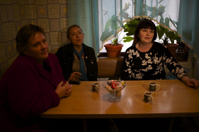 In this picture taken on Wednesday, Nov. 27, 2013, Alexandra Krivchenko, left, Nadezhda Kurovskaya, center, Irina Kharchenko, right, residents of 5a Akatsiy, street drink tea in the village of Vesyoloye outside Sochi, Russia. As the Winter Games are getting closer, many Sochi residents are complaining that their living conditions only got worse and that authorities are deaf to their grievances. (AP Photo/Alexander Zemlianichenko)