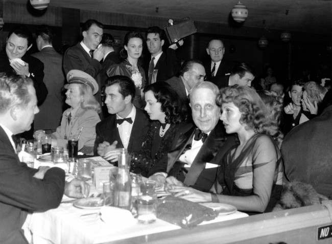 William Randolph Hearst is seen at a Military Ball in Hollywood, Ca. on April 15, 1942. Seated at the table in his row from left to right are: Marion Davies, in uniform, first medical battallion of California State Guard; actor George Montgomery; Hedy Lamarr; Hearst; Rita Hayworth.