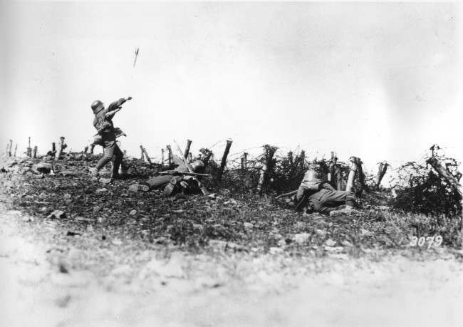 A German soldier throws a hand grenade against enemy positions, at an unknown battlefield during World War I