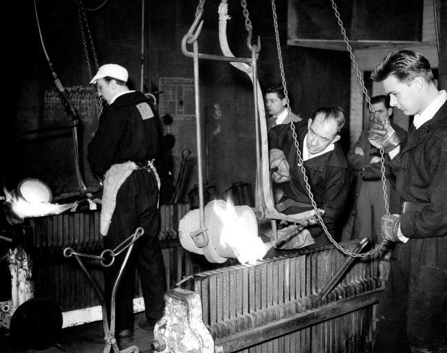 A worker pours molten gold into upright iron moulds - 1958