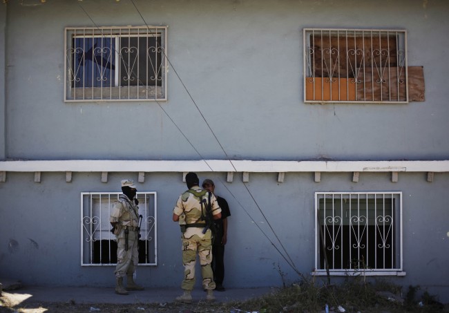 Soldiers talk to a suspect outside the house were the army found a tunnel under construction 40 yards from the border with the US in Tijuana, Mexico, Wednesday, July 8, 2009. (AP Photo/Guillermo Arias)