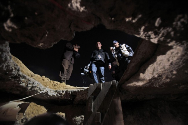 Members of the media stand outside a tunnel near the US-Mexico border in Tijuana, in Mexico, Tuesday, Oct. 27, 2009. Mexican soldiers have discovered a secret tunnel complete with electricity and an air supply that may have been planned for smuggling migrants or drugs under the U.S. border into San Diego (AP Photo/Guillermo Arias)