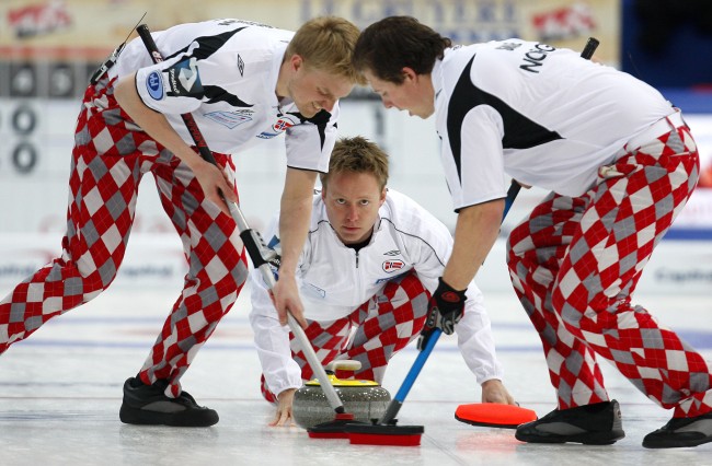 Norway's skip Torger Nergard throws his rock as first Havard Vad Petersson, left, and second Christoffer Svae sweep during a match against Sweden, at the Curling World Championships, in Cortina D'Ampezzo, Italy, Sunday, April 4, 2010. (AP Photo/Antonio Calanni) 