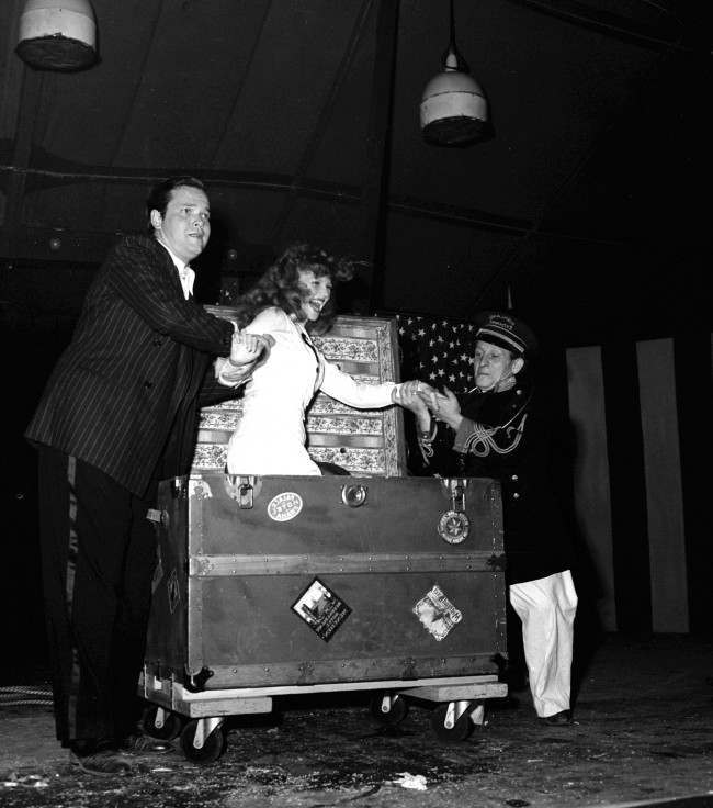 Soldiers cheered when Rita Hayworth, film star, was found again in a trunk, after Orson Welles, director-magician, had tied her in ropes and caused her to vanish on August 9, 1943 in Hollywood. (AP Photo)