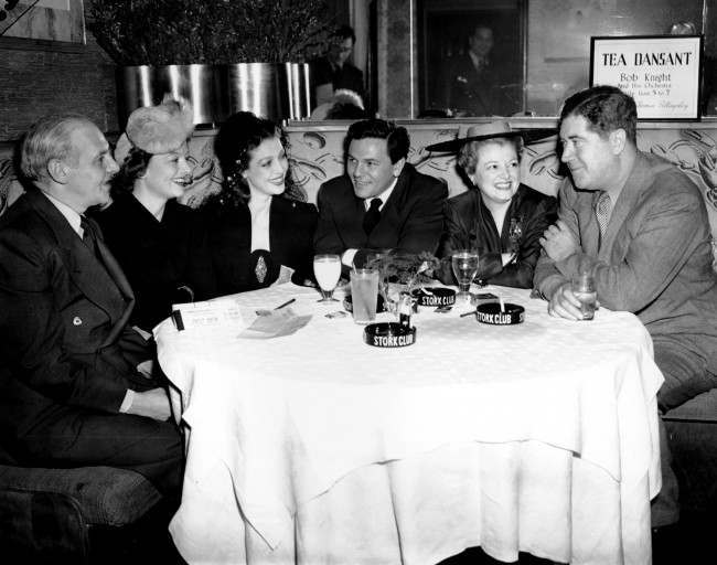 Writers and movie stars gather at New York's Stork Club, March 8, 1942, as they prepare for a World War II Navy Relief Show, two days away, at Madison Square Garden. From left are: columnist Walter Winchell, Myrna Loy, Loretta Young, John Garfield, Janet Gaynor and Quentin Reynolds, author and war correspondent. (AP Photo/Matty Zimmermann)