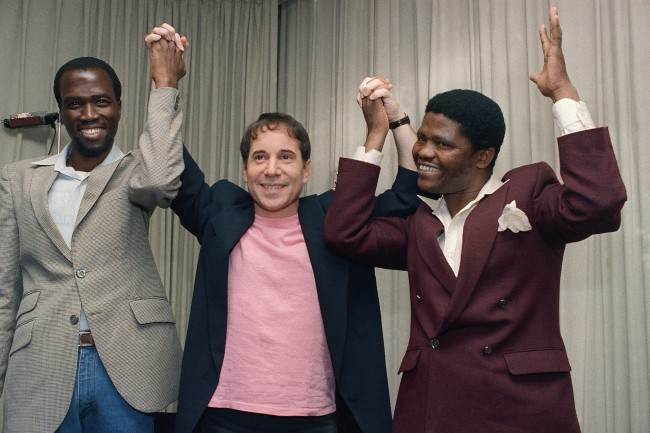 Singer-songwriter Paul Simon is joined by Albert Mazibuko, left, and Joseph Shabalala, right, at a news conference in New York, Aug. 25, 1986, to introduce Simon's new album, "Graceland." Mazibuko and Shabalala are two of the many South Africa musicians and singers who collaborated with Simon on his new album which blends the sounds of American pop music with that of black South Africa. (AP Photo/Marty Lederhandler)
