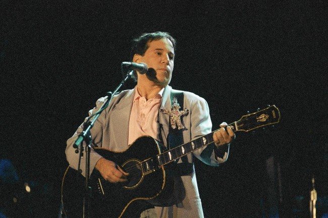 U.S. singer Paul Simon performs during his concert in Johannesburg, Jan. 11, 1992. Simon is the first international star to perform in South Africa since the lifting of the cultural boycott last year. A small group of black militants staged a demonstration outside the stadium. (AP Photo/Adil Bradlow)
