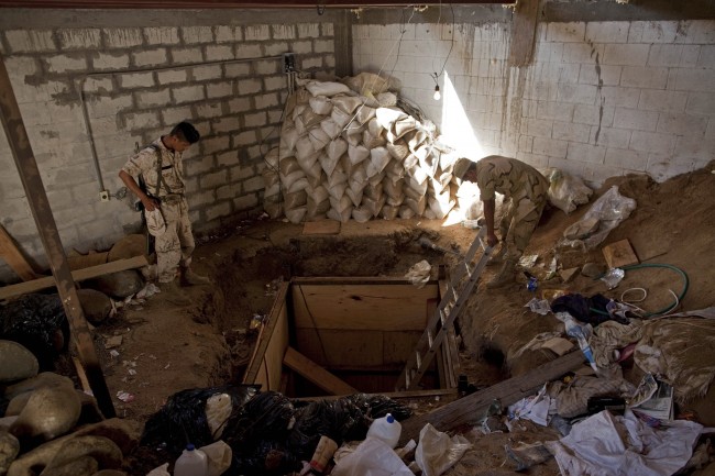 Mexican Army soldiers custody the entrance of a clandestine tunnel connecting warehouses on either side of California's border with Mexico in Tijuana, Thursday, Nov. 4, 2010. Federal authorities in San Diego made one of the largest marijuana seizures in the United States, confiscating more than 20 tons of pot that was smuggled to the country through the underground tunnel that had lighting, ventilation and a rail system to send loads of illegal drugs into California. Mexican authorities also seized more than four tons of drug from the warehouse on their side. (AP Photo/Guillermo Arias)