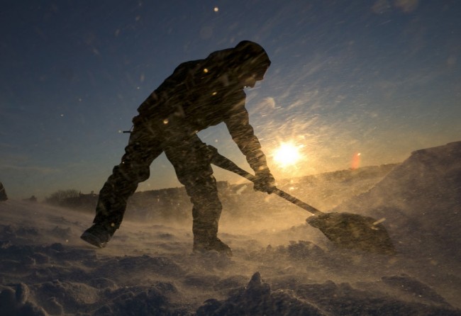 Fierce winds blow snow as snowboarder Garrett Ramos, 20, uses a shovel to build a jump in Portland, Maine, on January 3, 2014. (AP Photo/Robert F. Bukaty)