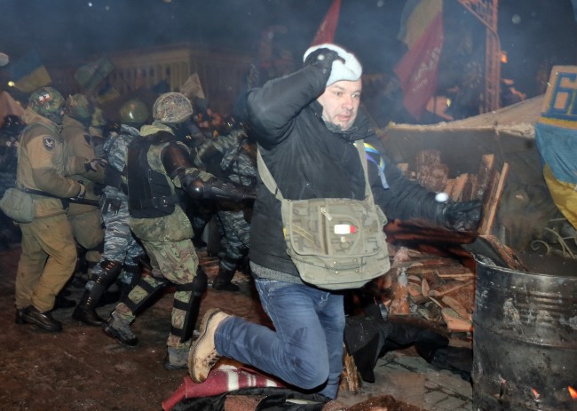 An Pro-European Union activist runs during clash with riot police on the Independence Square in Kiev, Ukraine, Wednesday, Dec. 11, 2013. Security forces clashed with protesters as they began tearing down opposition barricades and tents set up in the center of the Ukrainian capital early Wednesday, in an escalation of the weeks-long standoff threatening the leadership of President Viktor Yanukovych. 