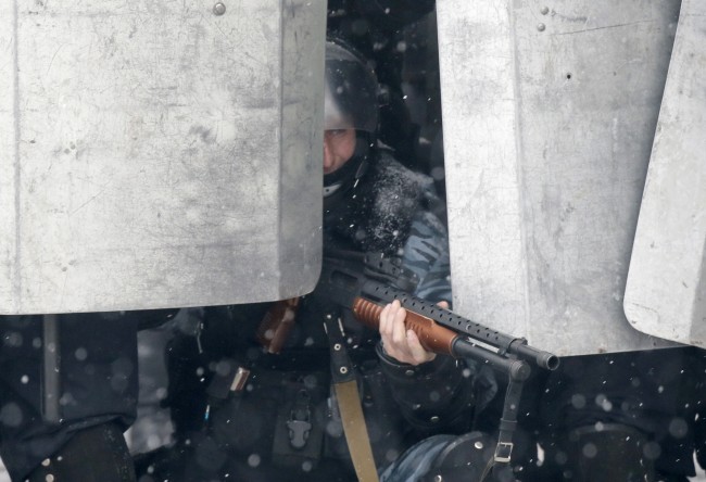 A police officer aims his shotgun during clashes with protesters in central Kiev, Ukraine, Wednesday, Jan. 22, 2014. City health officials and police said that two people died of gunshot wounds during the clashes Wednesday morning. But the opposition charges that as many as five people have died. The mass protests in the capital of Kiev erupted after Ukrainian President Viktor Yanukovych spurned a pact with the European Union in favor of close ties with Russia, which offered him a $15 billion bailout. 