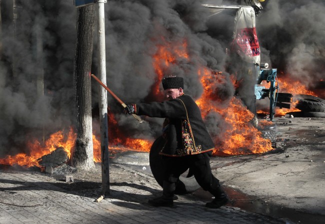 An anti-government protester threatens riot police outside Ukraine's parliament in Kiev, Ukraine, Tuesday, Feb. 18, 2014. Thousands of angry anti-government protesters clashed with police in a new eruption of violence following new maneuvering by Russia and the European Union to gain influence over this former Soviet republic.