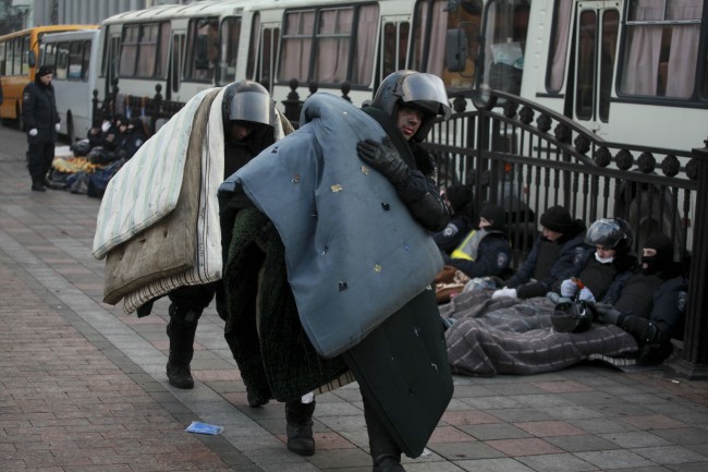Police officers carry mattresses to take a rest at Ukraine's parliament in Kiev, Ukraine, Thursday, Feb. 20, 2014. Ferocious street battles between protesters and police in the Ukrainian capital have left dozens dead and hundreds wounded in the past few days, raising fears that the ex-Soviet nation, whose loyalties are split between Russia and the West, is in an uncontrollable spiral of violence.
