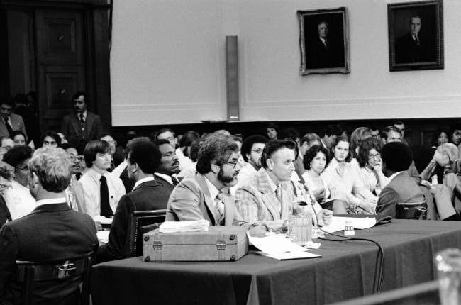 James Earl Ray sits with his attorney Mark Lane during testimony before the House Assassinations Committee in Washington, August 16, 1978. Federal marshals form a ring around ray and the attorney as they sit with their books to the table facing the audience. 