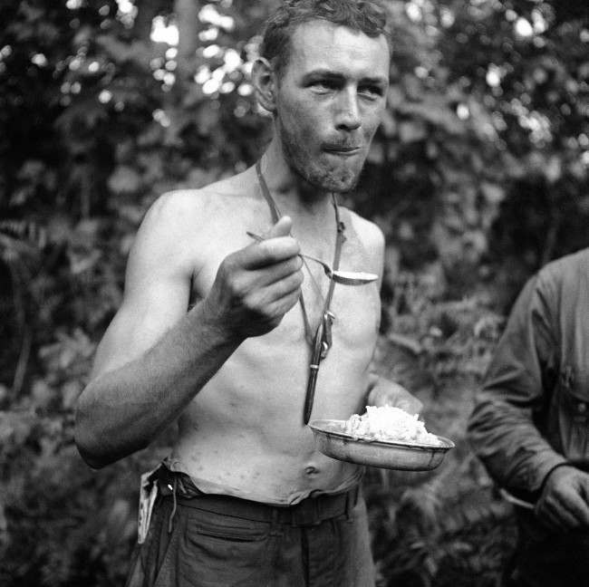 This unidentified U.S. soldier eats his first hot meal after 11 days in the jungles of New Guinea on Dec. 26, 1942, where he not only contended with Japanese who surrounded his group the last two days, but fought insects which raised welts on his mid-section.