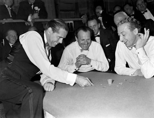 Tiddlywinks - World Championship Tiddlywinks Match - Cambridge University v The Empress Club - Empress Club, London The Earl of Kimberley, left, squidges for the pot, watched by Terry Thomas (centre) and Kevin McClory.