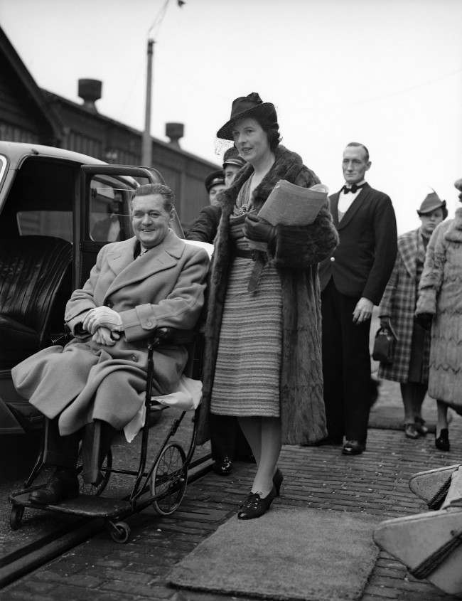 Derek McCulloch, Uncle Mac of the B.B.C., sailed on a cruise to Portugal to recover from his fortieth operation, the amputation of a leg. Derek McCulloch in his invalid chair with his wife,Eileen, at Southampton, England, on Feb. 17, 1939, before embarking in the liner Asturias. (AP Photo) Date: 17/02/1939