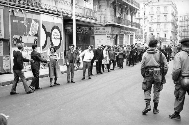 Long line of Europeans pass supplies by hand along an Algiers street, with the supplies eventually going to inhabitants of besieged Bab-el-Oued sector, March 25, 1962. The rightist stronghold has been encircled by French government troops on orders from President de Gaulle to smash the European secret army revolt.