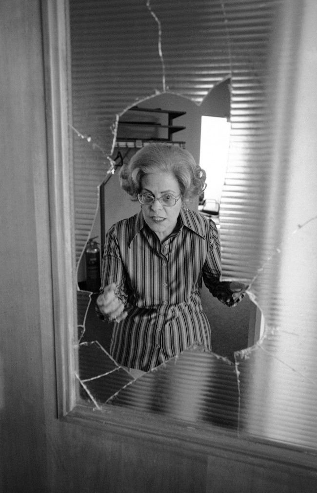 Rae Ehrlich is framed by a broken glass partition, at BÂnai BÂrith headquarters in Washington on Sunday, March 14, 1977 as she explains how gunmen broke the glass with a rifle butt and took her and others hostage. Over a hundred captives were held for 38 hours.
