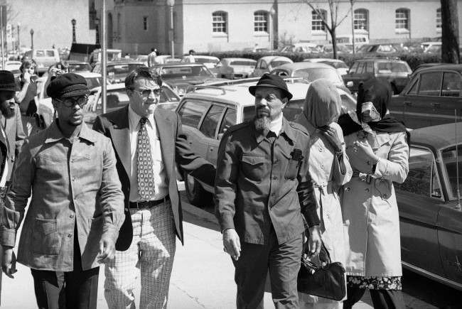 Hamaas Abdul Khaalis, Hanafi Muslim leader, arrives at district court on Thursday, March 31, 1977 in Washington along with his two veiled wives where a preliminary hearing was to be held on charges stemming from the siege of three buildings in Washington along with hostages.