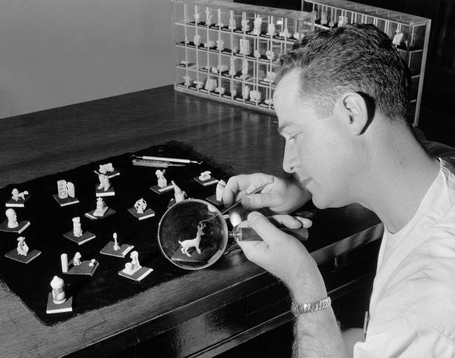 With the aid of a magnifying glass, Doyle J. Davis, freshman dental student at the University of Southern California, carves a miniature deer, April 7, 1955. ItÂs class work, not a hobby. Because hand skill is important to a dentist, Dr. William P. Harrison, who conducts a dental anatomy class at the university, originated 25 years ago a creative wax-carving test to determine the manual dexterity of his freshman students. His campus office contains some 3,000 miniature objects which the students carved from tiny cylindrical pieces of hard caruba wax only 1-inch high and three-quarter of an inch wide. 