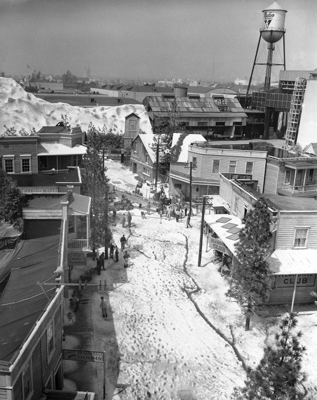 When moviemakers in Hollywood want to make a picture depicting a far off land they donÂt necessarily have to go there to make the film. With a bit of ingenuity, the know-how and a lot of dollars to spend they just build the locale in their back lot. This street scene, with real snow depicts an Alaskan town and was laid out on the Paramount lot in Hollywood, March 31, 1953. In the background, the RKO Studio The scene, snow, buildings, mountain, dogs and people used in the cast, ran up to a cost of about $180,000. 