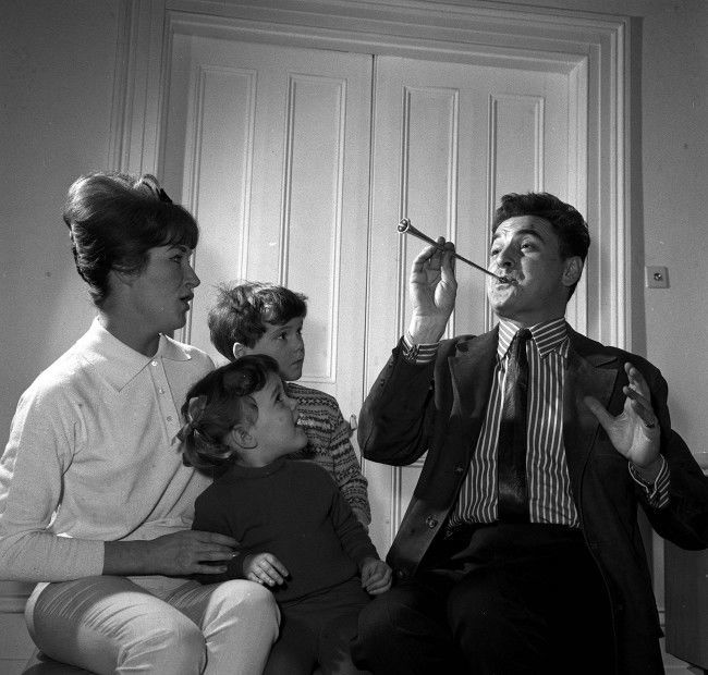 Scripwriter and comedian Bob Monkhouse with his family, wife Elizabeth, son Simon (centre behind), and adopted daughter Abigail, in their St John's Wood home in London. * 11/05/01 The son of Bob Monkhouse has been found dead in Thailand, a Foreign Office spokesman said. The body of Simon Monkhouse, 46, was found in Bangkok on April 14 but details of his death were only released today, a spokesman said. Mr Monkhouse, from Lambeth, south London, was holidaying alone in Bangkok when his body was found in a hotel, the Sun said. 12/5/01: Monkhouse's ex-wife Elizabeth, Saturday May 12, 2001 told for the first time how she was struggling to cope with the death of her son Simon in Thailand. She said she felt "utterly bereft" to lose a second child after the couple's son Gary died nine years ago and revealed that the last time she heard from Simon, 46, he was"healthy, happy and having the holiday of a lifetime". Meanwhile 72-year-old Monkhouse, who admitted falling out with his son years ago, said he was heartbroken that he would never get the chance to have a reconciliation with him. *29/12/03: Veteran British comedian and television host Bob Monkhouse who died, aged 75, after losing a lengthy battle with prostate cancer.  Ref #: PA.1253487  Date: 23/02/1962