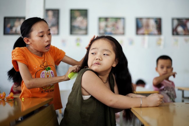 In this photo taken Aug. 7, 2012, Ho Thi Lang, left, combs Ngo Diep Uyen's hair after her nap at a rehabilitation center in Danang, Vietnam. 