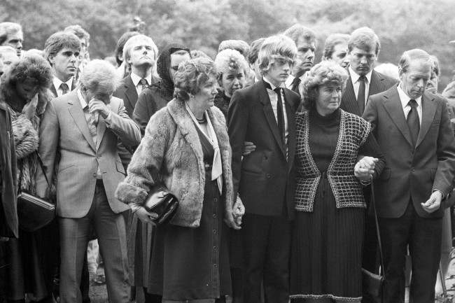 Wiping away a tear (l) is comedian Freddie Starr and his wife Sandy at the requiem mass of actor Alan Lake at the Sacred Heart Catholic Church in Sunningdale. Picture behind Freddie Starr is Max Clifford. Archive-PA211617-6 Ref #: PA.15027776  Date: 17/10/1984