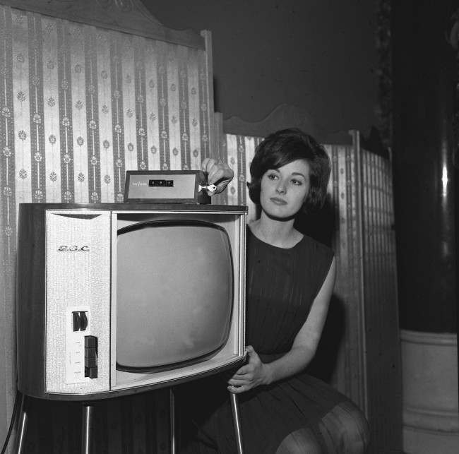 Diana Stones, 20, turns the key prior to selecting the desired channel on a TV set equipped with the new Marconi PayVision system in a London demonstration. The unit, a small box no larger than the average book, plugs into the aerial socket of any standard TV set and push-buttons select various PayVision channels. It costs only 5 to instal and average cost of programmes is 2/6d, with some public service and educational prgrammes free of charge. A central billing exchange automatically registers all programmes viewed. PayVision uses a closed circuit distribution system to bring three new TV channels into the home. The unit can be used with existing sets and does not affect present programme reception.