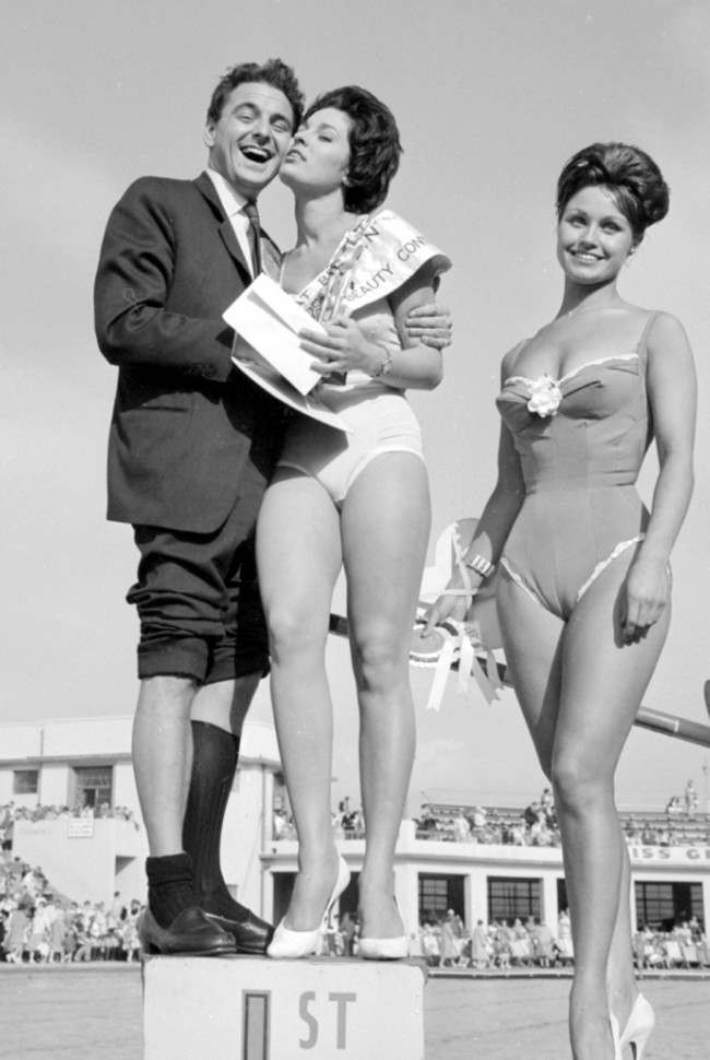 Head of the panel of judges, Bob Monkhouse gives a hug to 23-year-old Eileen-Elizabeth Sheridan of Walton-on-Thames, Surrey, after she had won the title of Miss Great Britain, at Morecambe, Lancashire. To their right is runner up Barbara Smith,23, of Walthamstow, London. *29/12/03: Veteran British comedian and television host Bob Monkhouse who died, aged 75, after losing a lengthy battle with prostate cancer.  Ref #: PA.1855119  Date: 01/09/1960