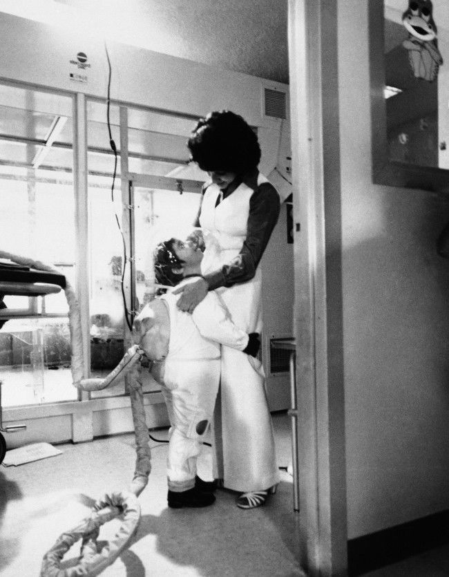 Little David Vetter, the six-year-old "bubble baby", gives his mother Carol Ann Vetter, a hug while wearing his new Mobile Isolator System, in Houston, Nov. 4, 1977. David suffers from Severe Combined Immune Deficency Syndrome (SCIDS) The suit is a germ-free space type suit that enables David to leave his germ-free bubble that he has lived in since birth. The long hose attached to David's back is a live-support system that pumps air into the suit. (